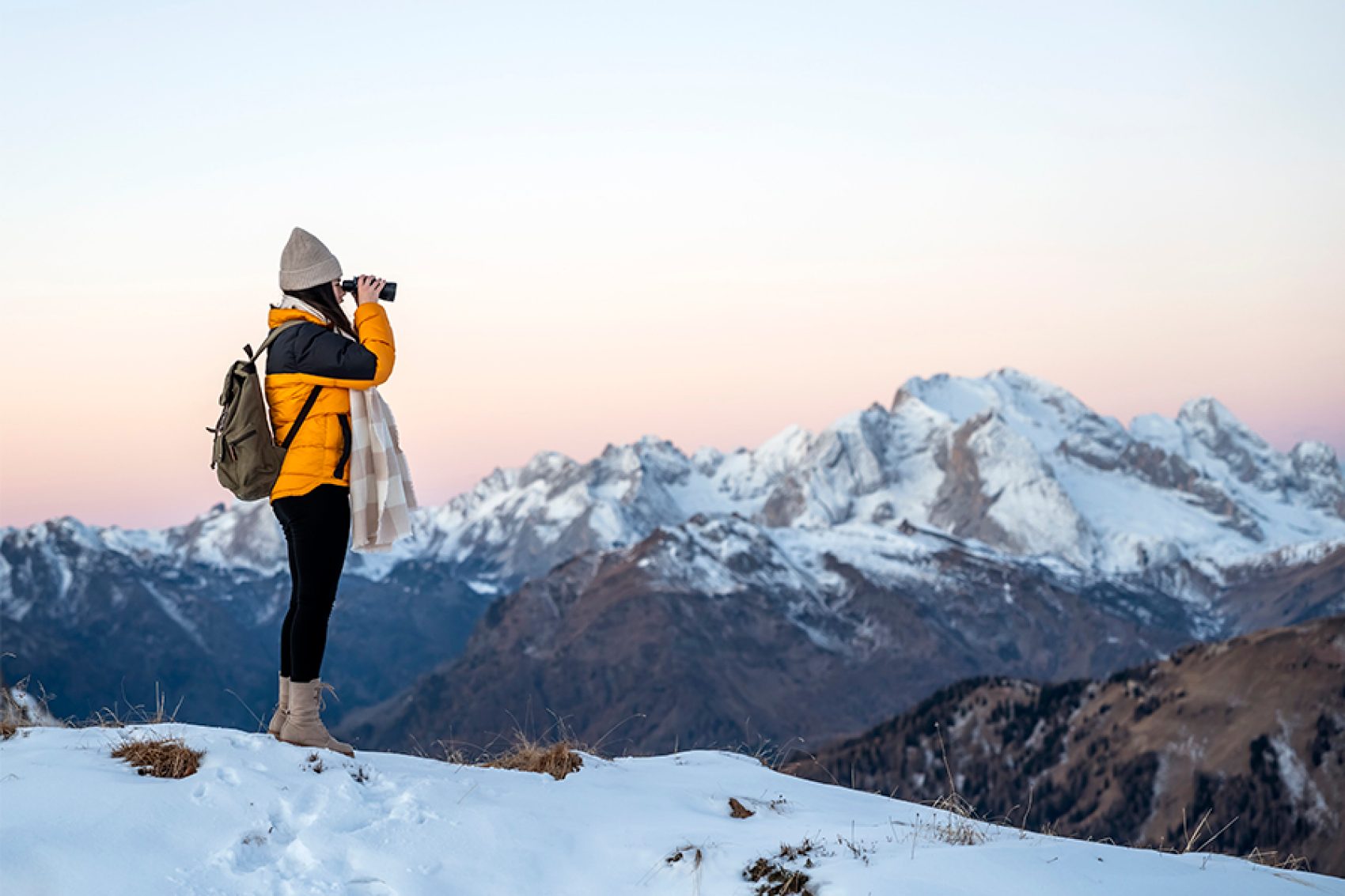 Person using binoculars to view snowy mountains
