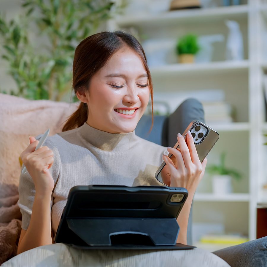 Woman using an iPad and smiling at her phone
