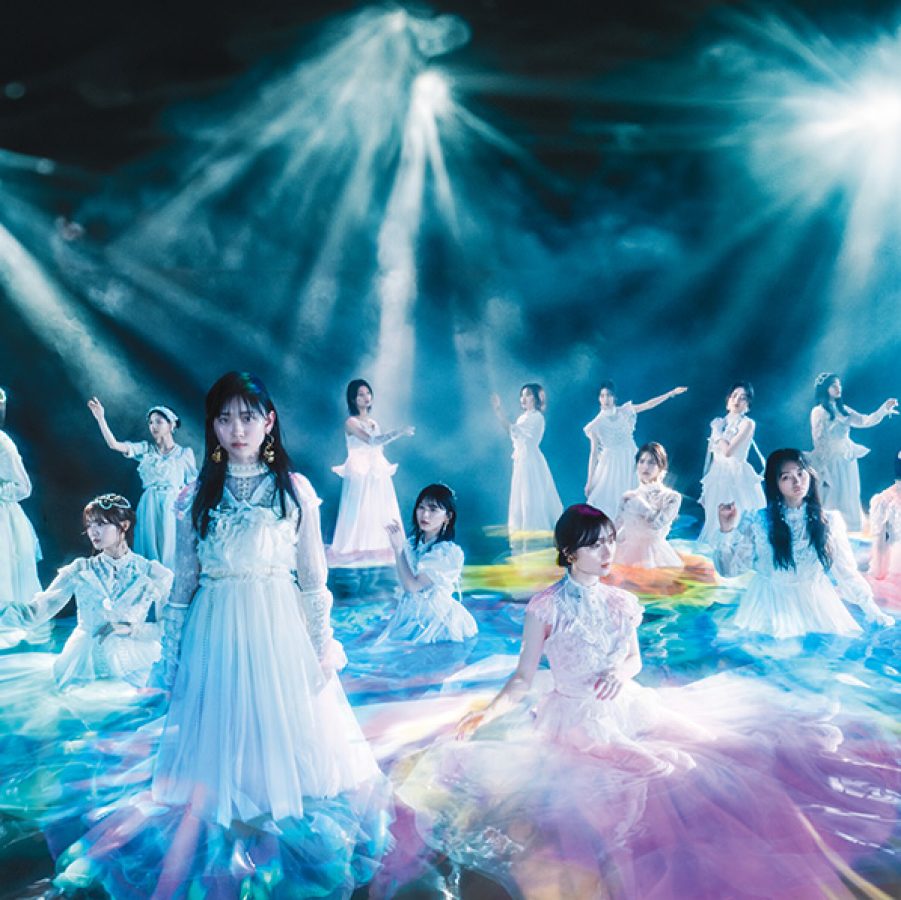 Japanese pop band Sakurazaka46. 14 members all wearing white dresses are pictured under dramatic stage lighting. 