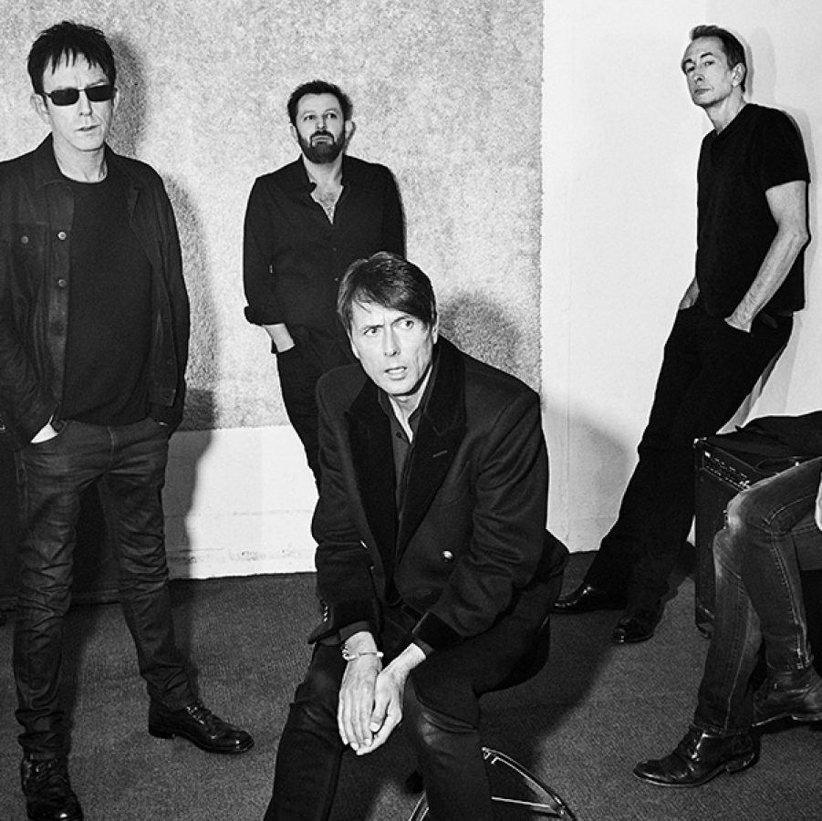 A black-and-white photo of Britpop band Suede standing and sitting in a room.