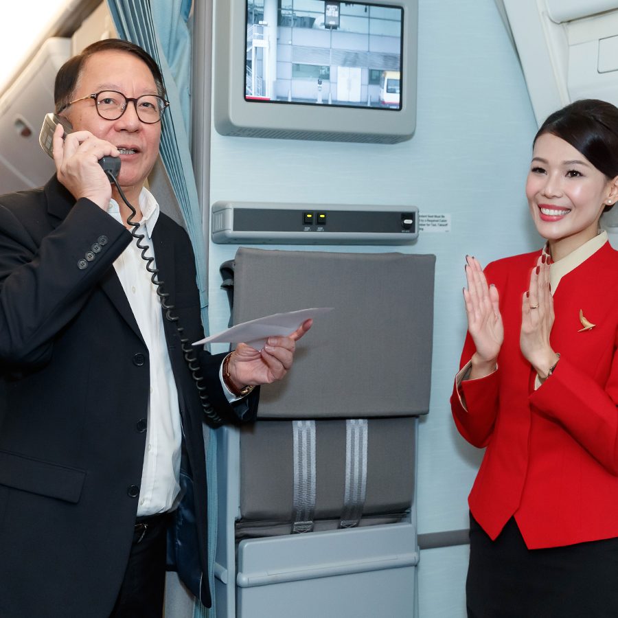 A Cathay Pacific cabin crew member claps as a member of the team makes an announcement onboard a Cathay Pacific Community Flight.