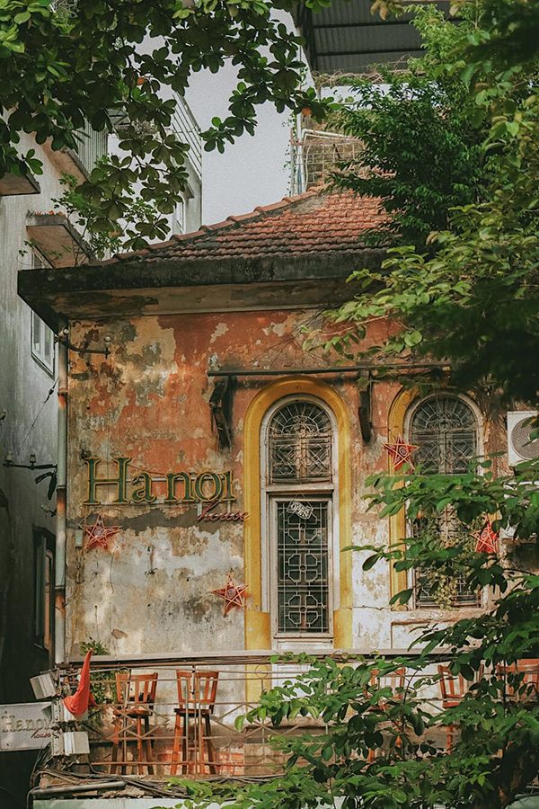 The exterior of Hanoi House framed by green foliage in the daytime.