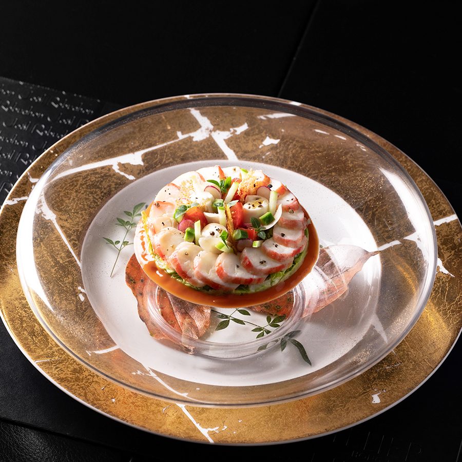 Slices of crab meat are elegantly presented on a glass plate. 