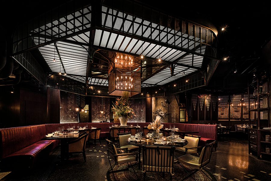 Lounge-style seating is spread across a sumptuous room softly lit by hanging pendant lights.