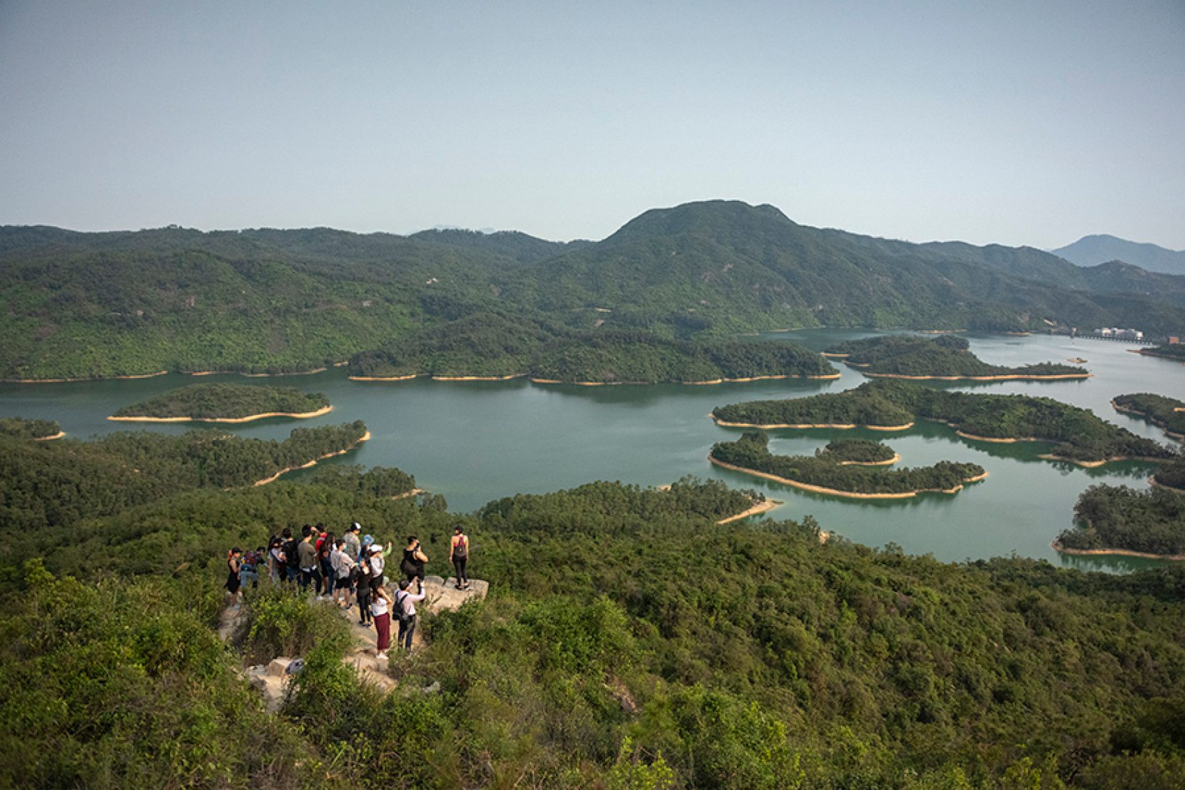 Aerial shot of Tai Lam Chung Reservoir, with a group of hikers looking out at the view. 
