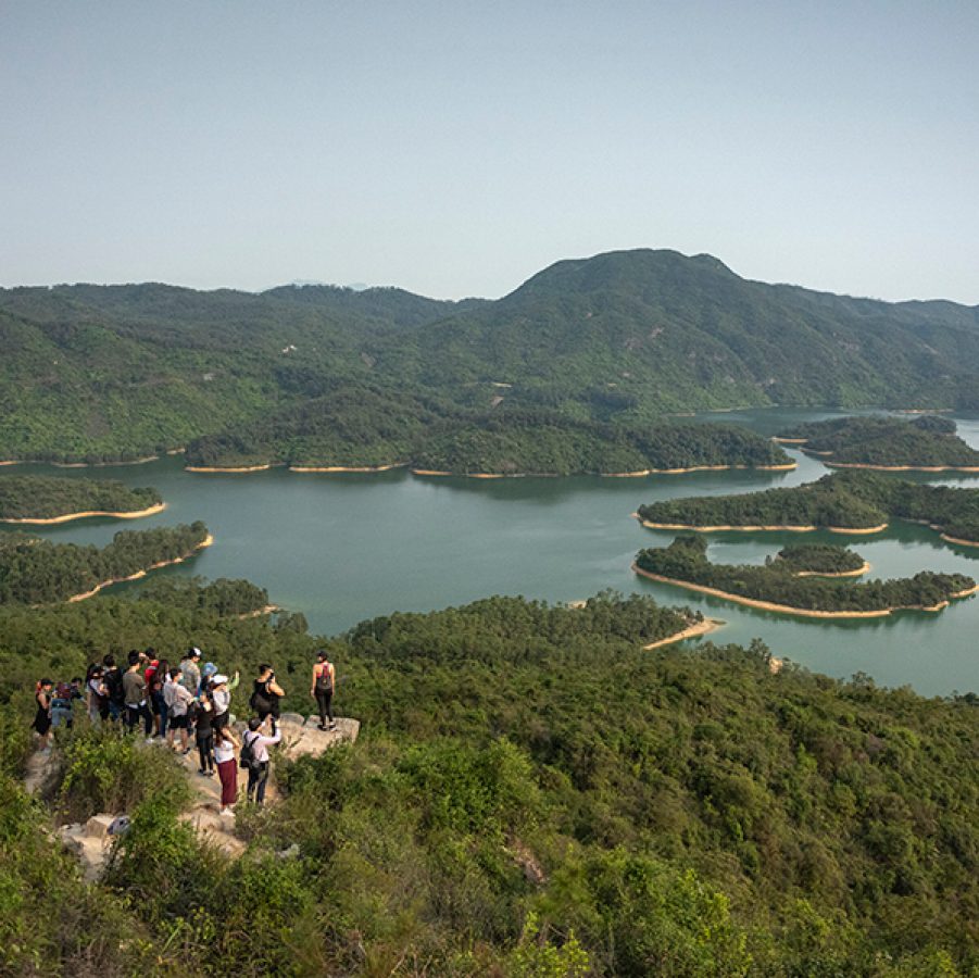 Aerial shot of Tai Lam Chung Reservoir, with a group of hikers looking out at the view. 