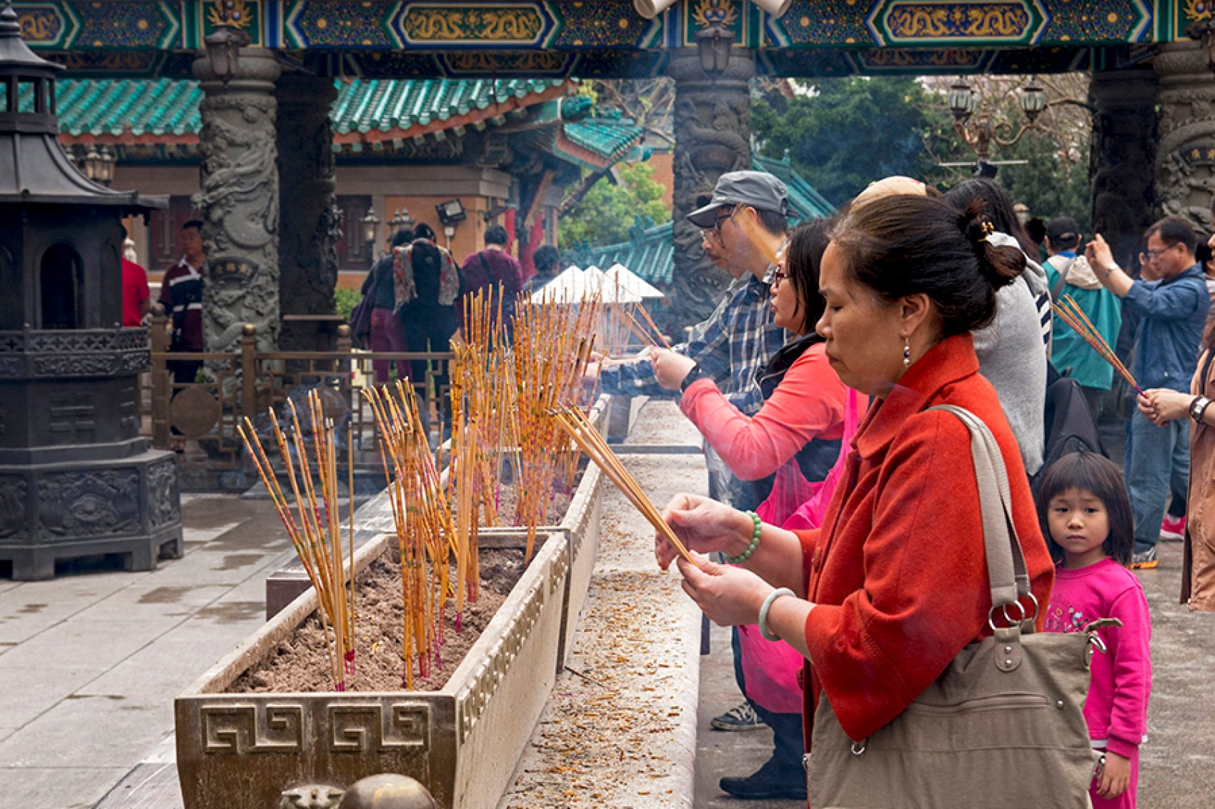 People holding incense sticks at a temple. 