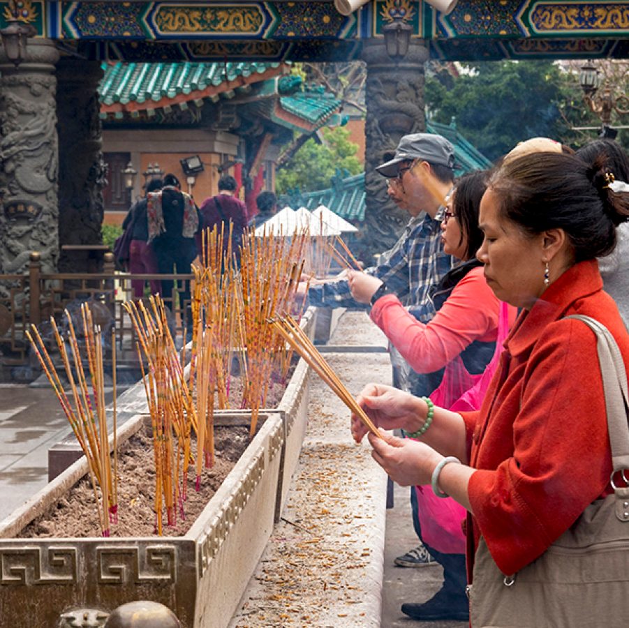 People holding incense sticks at a temple. 