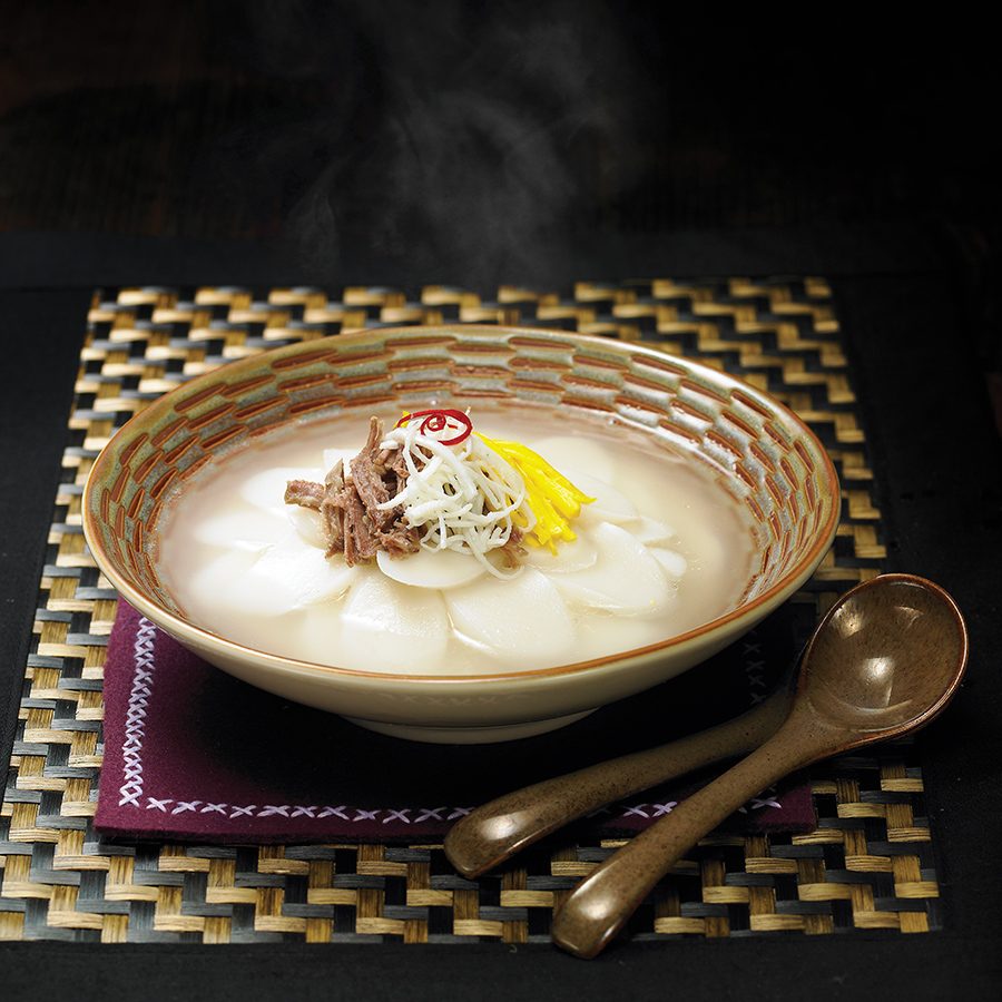 Close up of a tteokguk dish served in a golden bowl.