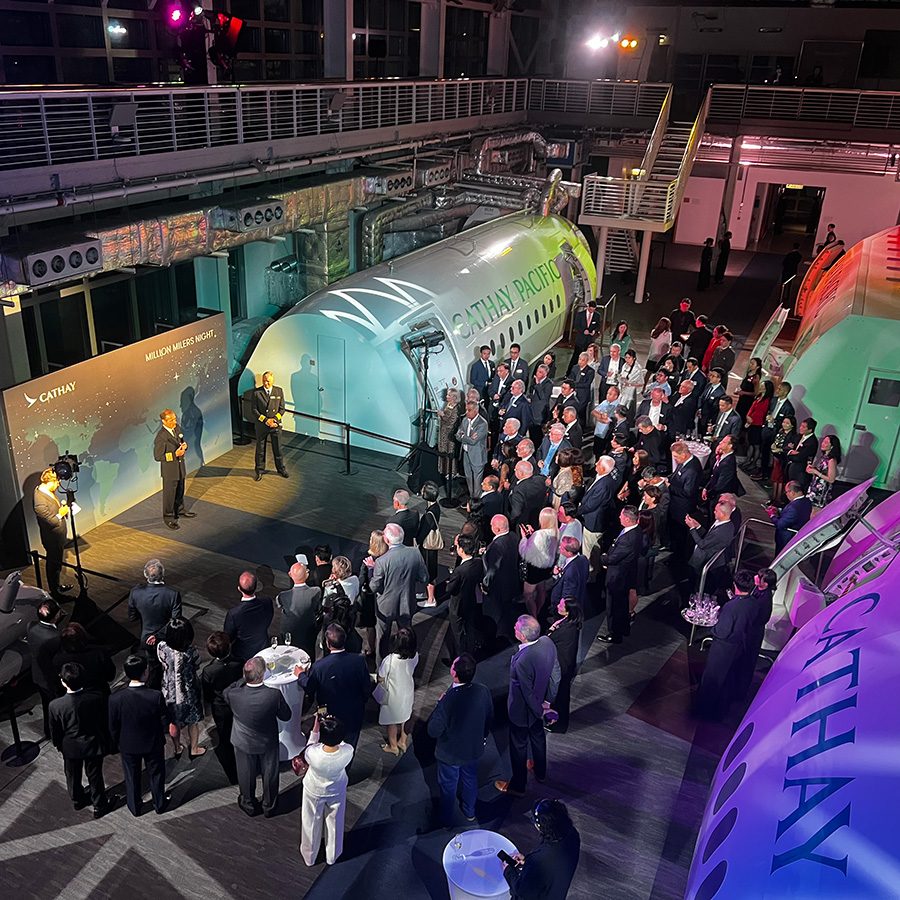 An aerial shot of Cathay senior leadership welcoming the Million Milers into the unique space of the Flight Training Centre, with lights illuminating the various training models of Cathay’s aircraft cabins.