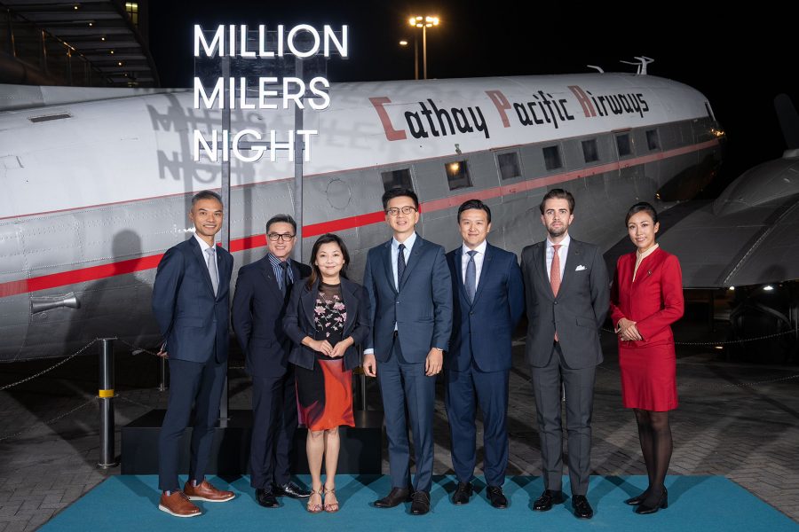 Cathay senior leadership pose for a photo in front of a sign that says “Million Milers Night” and a plane with the old Cathay Pacific livery. 