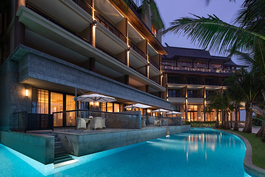 A exterior view of Angsana Zhuhai Phoenix Bay resort hotel guestrooms in the evening with direct access to the private pool on the terrace. 