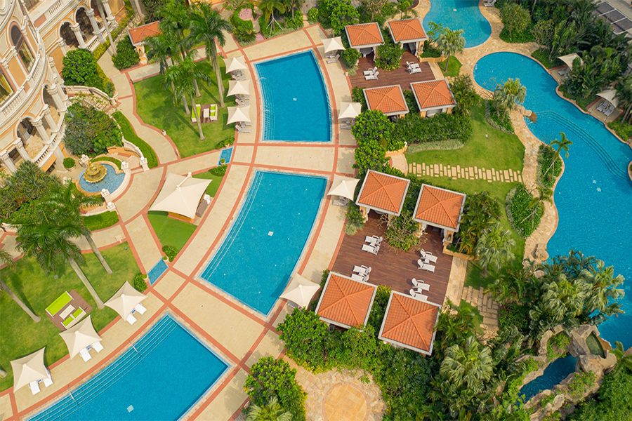 An aerial shot of Four Seasons Macao and a view of the hotel’s multiple outdoor pools during daytime.
