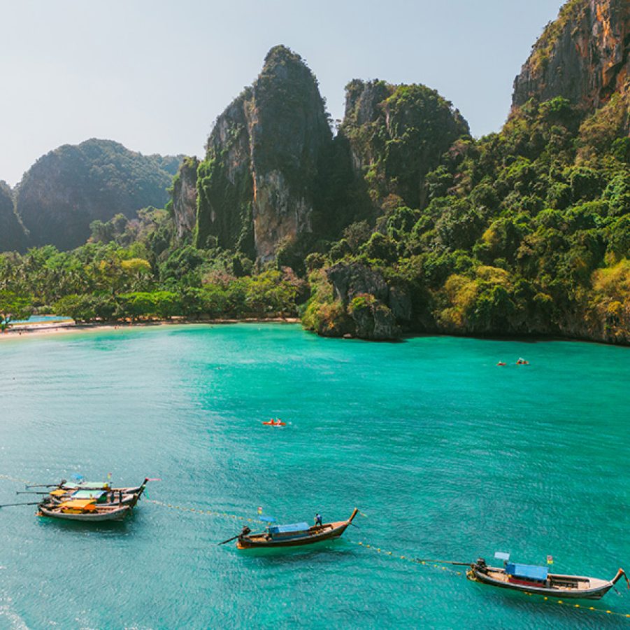 Limestone cliffs behind boats in the water at Krabi. 