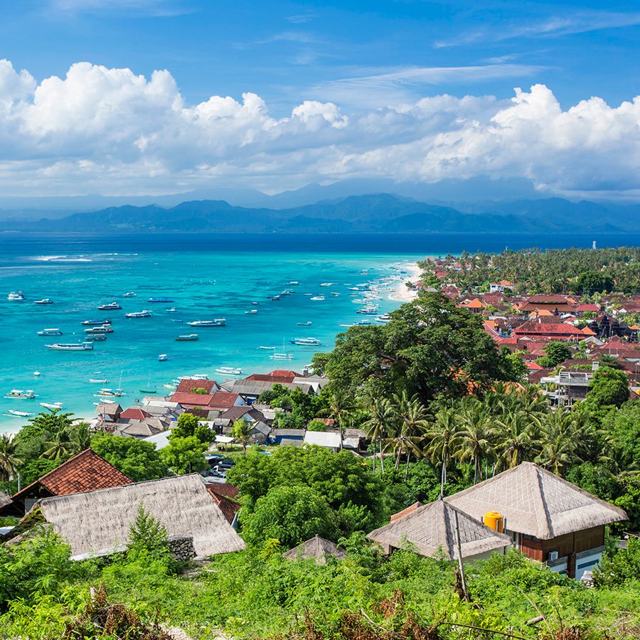 Wide shot of houses and trees by the beach in Nusa Lembongan. 