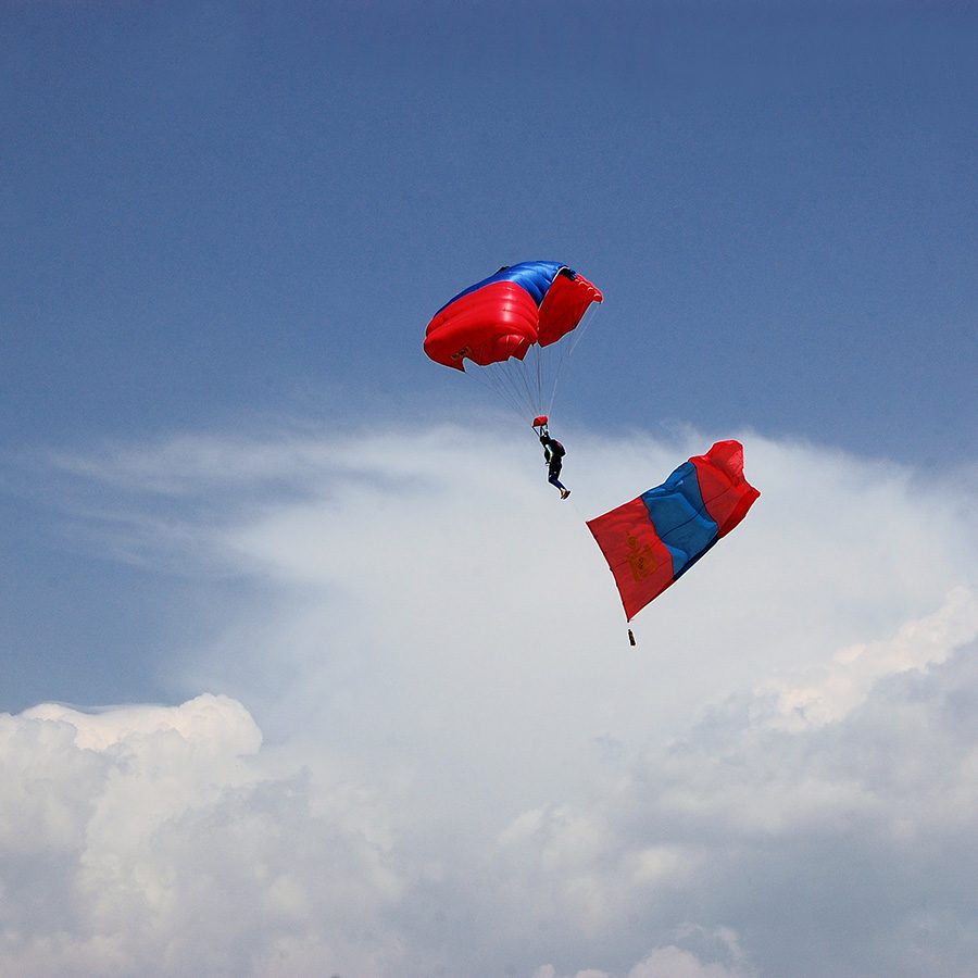 Man paragliding with a Mongolian flag.