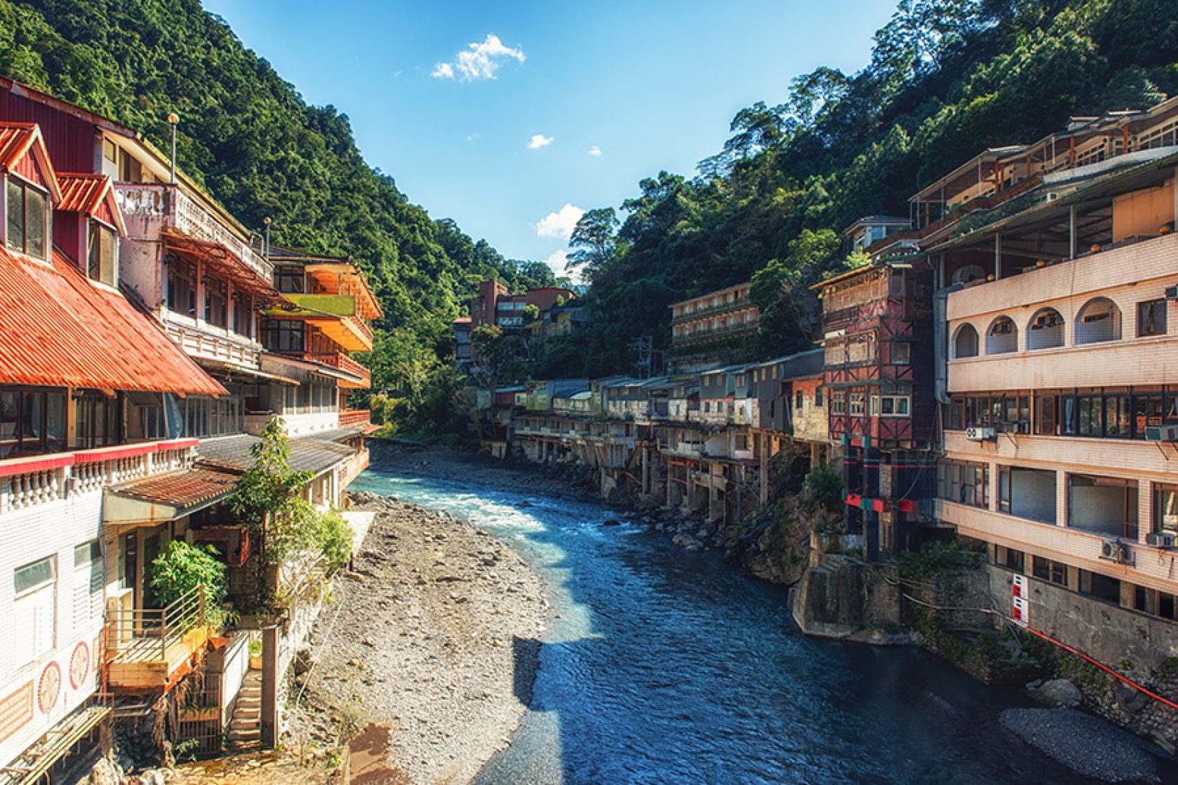 Colourful buildings and trees bordering the river running through the town of Wulai. 