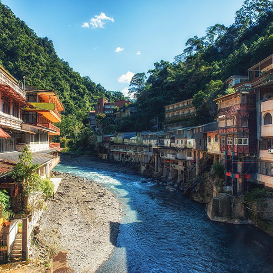 Colourful buildings and trees bordering the river running through the town of Wulai. 