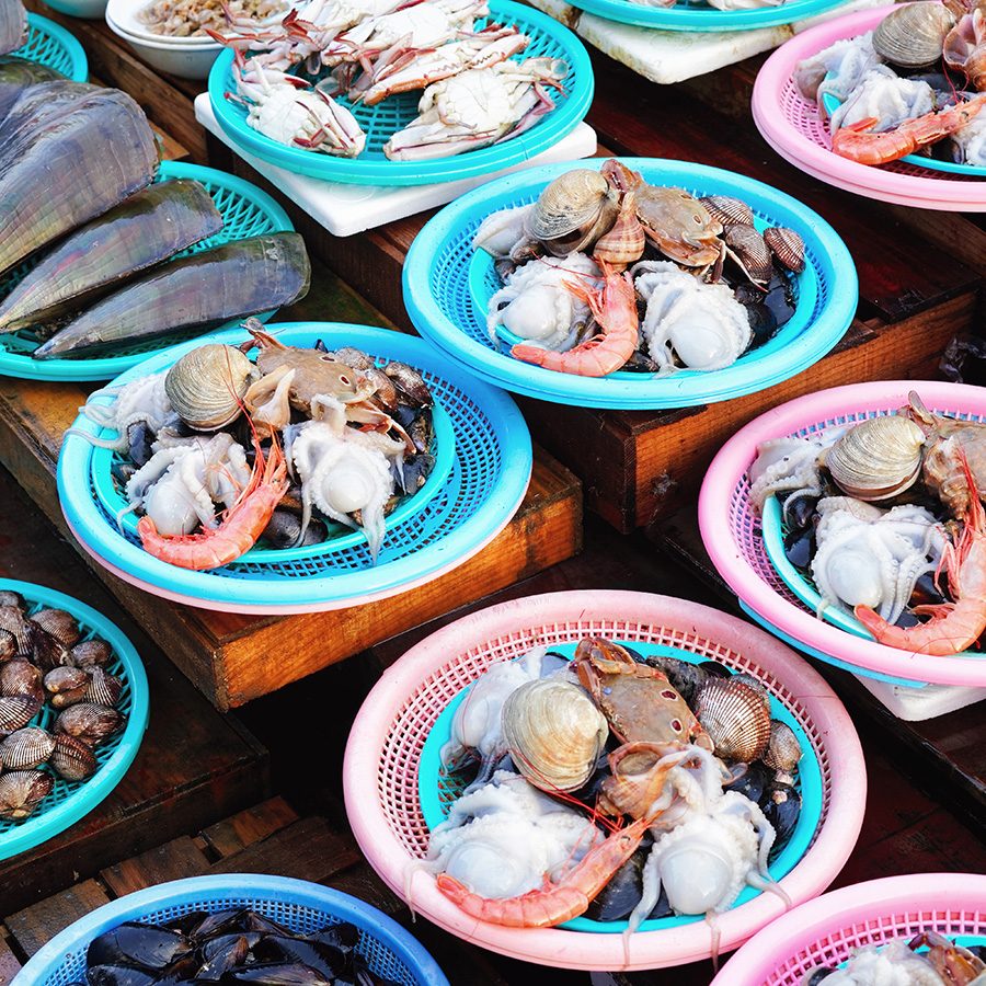 Seafood in pink and blue plastic baskets. 