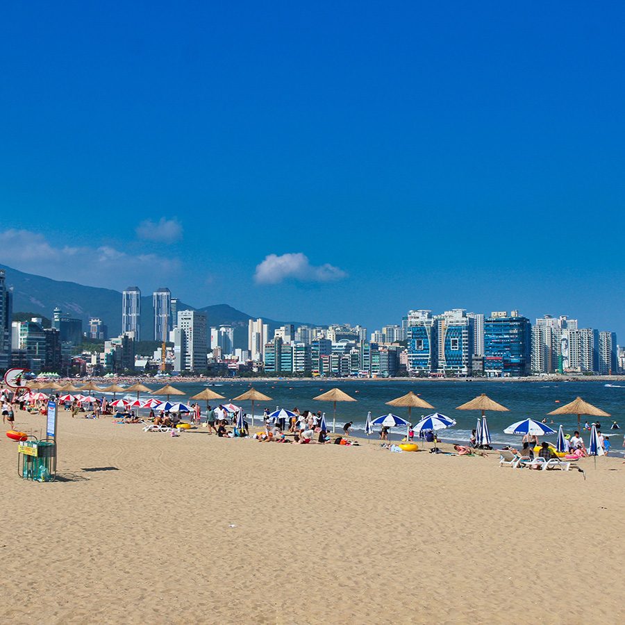 Wide shot of Gwangalli Beach, with skyscrapers in the distance. 