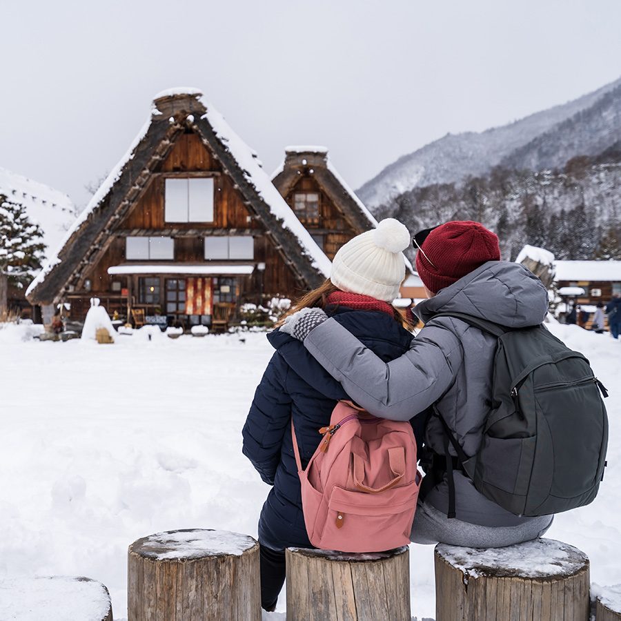 Two people sitting in front of a farmhouse at Shirakawa-go. 