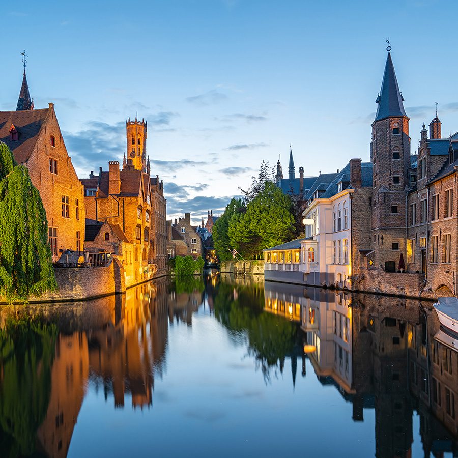 Evening view of Bruges’ canal system and old-fashioned buildings along the water. 