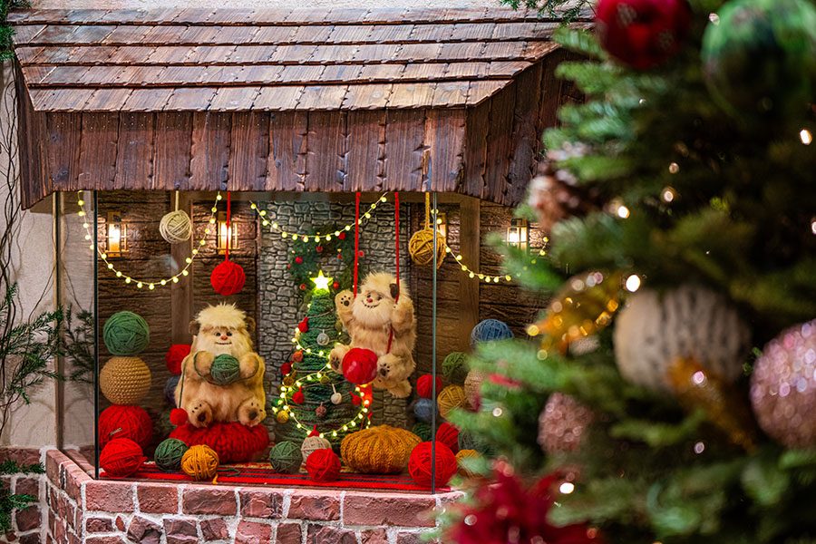 A display shows furry monster figures playing with balls of wool, while part of a Christmas tree can be seen. 
