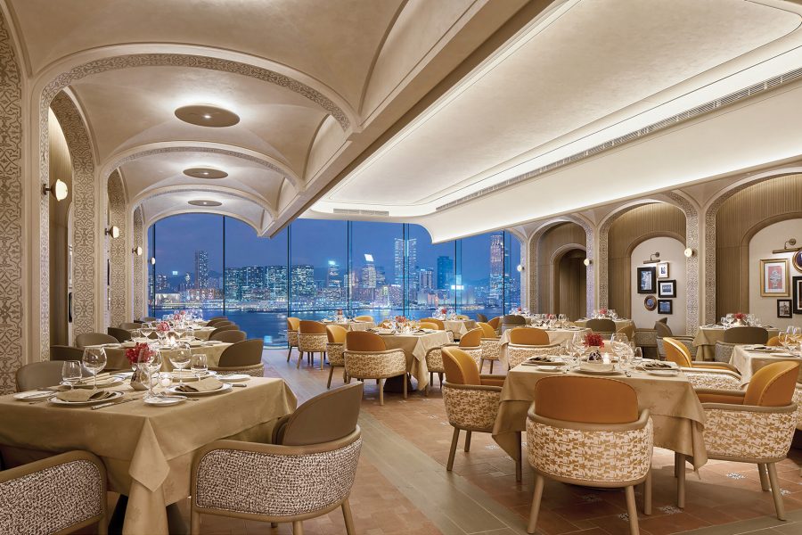 The interior of Sabatini Ristorante Italiano in Hong Kong. The skyline at night can be seen through a large window.