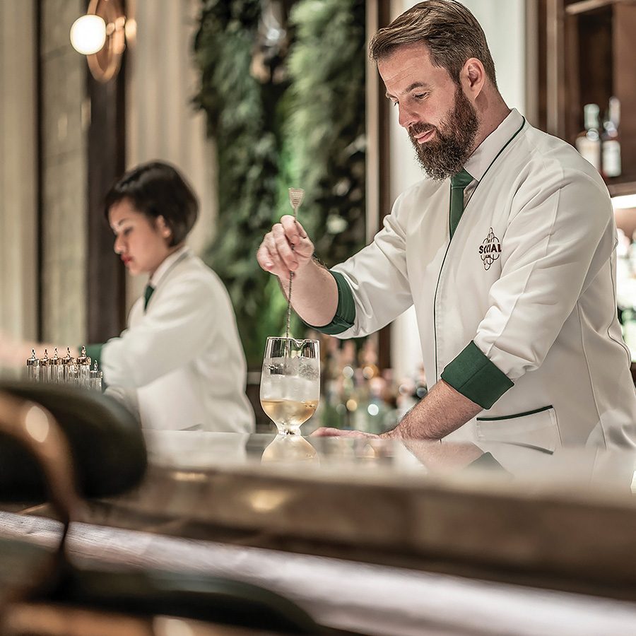 Philip Bischoff, bar manager at BKK Social Club, mixing a drink for a customer behind the bar.
