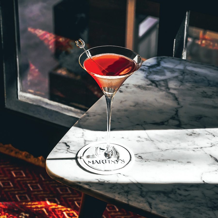 A drink being served with a garnish in a martini glass on top of a coaster at Martiny’s in New York.