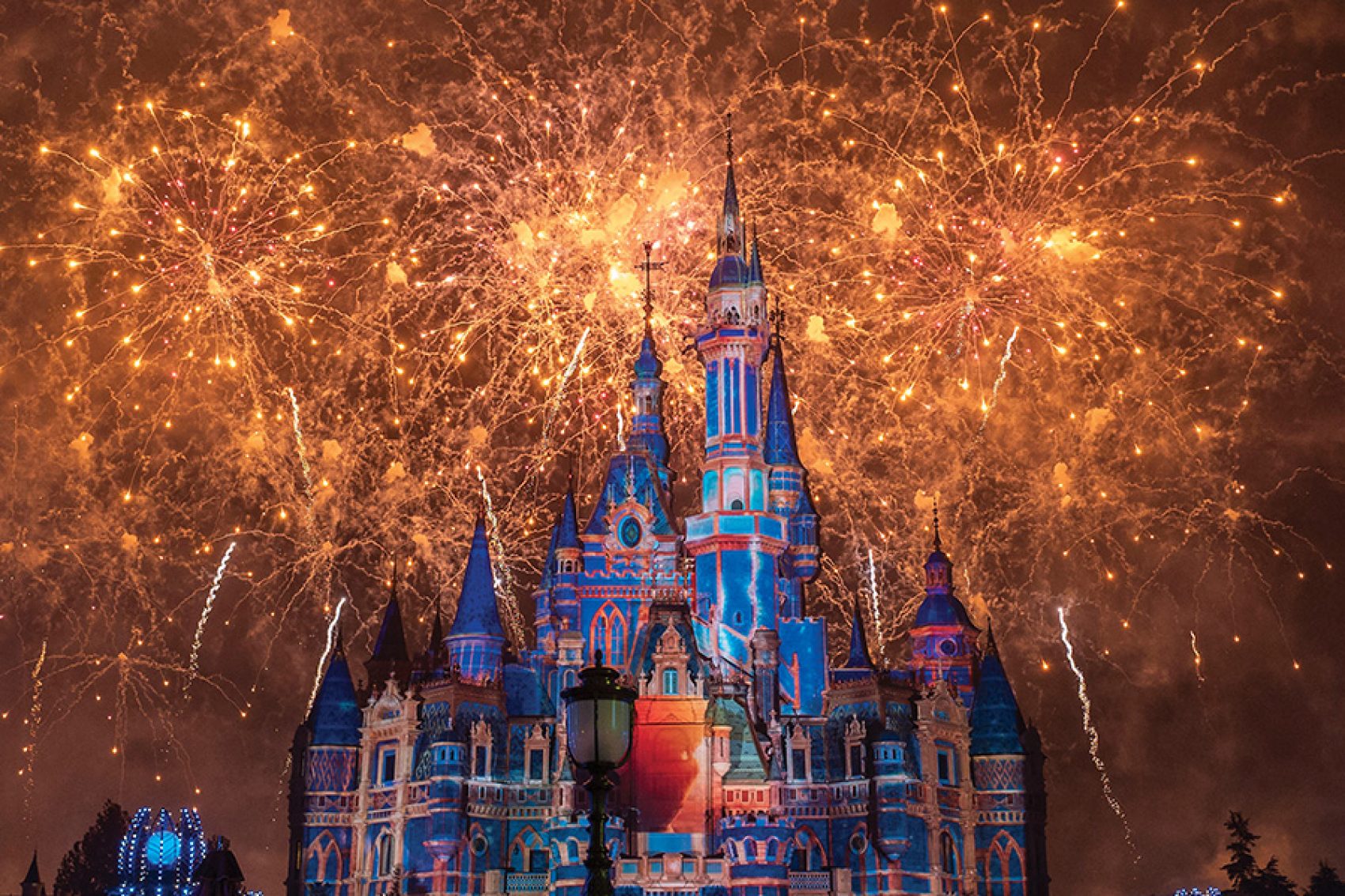 Bright golden fireworks light up the night sky behind the Enchanted Storybook Castle at Shanghai Disneyland.