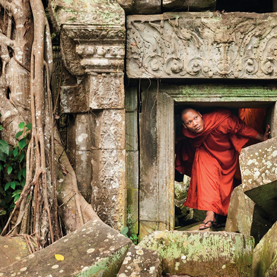 Cambodian monk ducks through an archway in a temple ruin in Cambodia.
