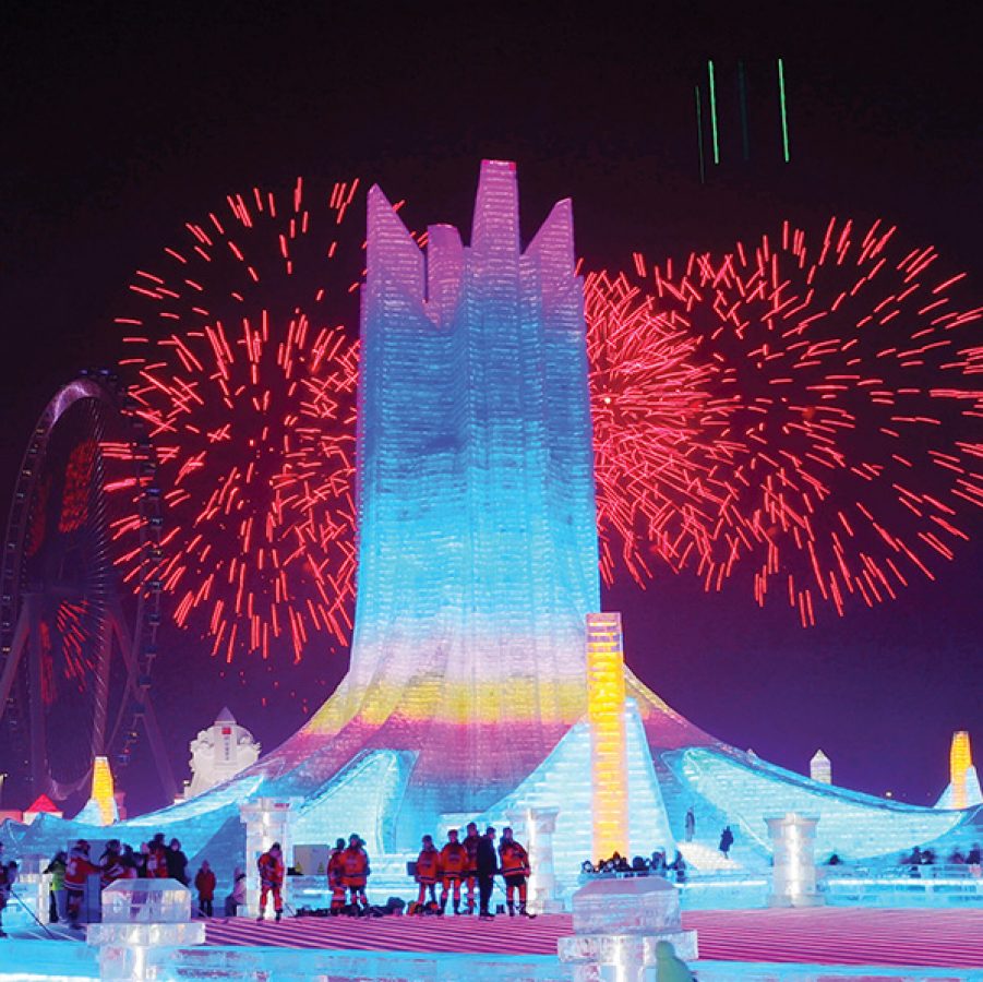 Gigantic ice sculpture tower with fireworks bursting behind it at Harbin Ice and Snow World.