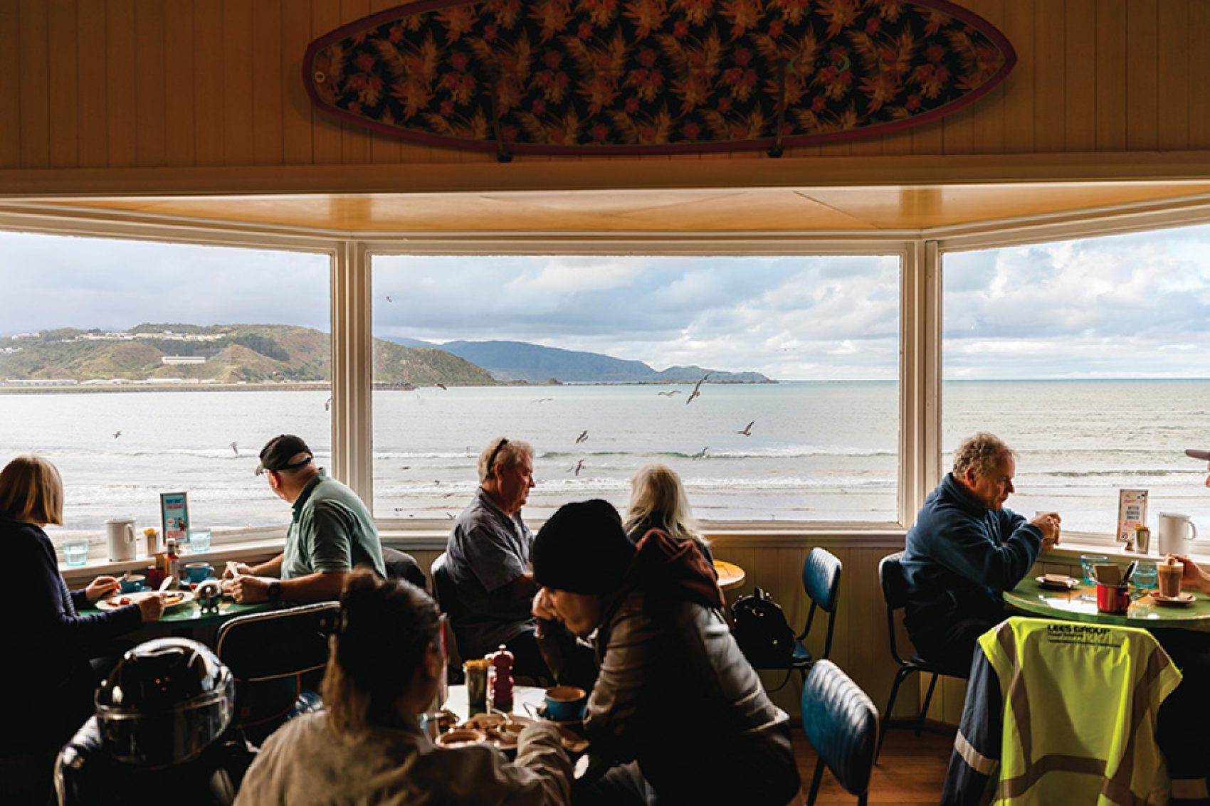 Diners sitting by the window at Maranui Cafe, with views of Lyall Bay.