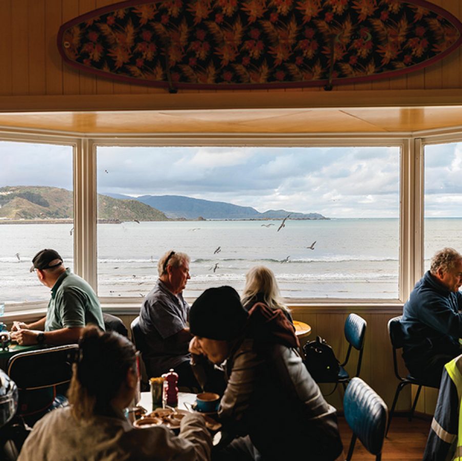 Diners sitting by the window at Maranui Cafe, with views of Lyall Bay.