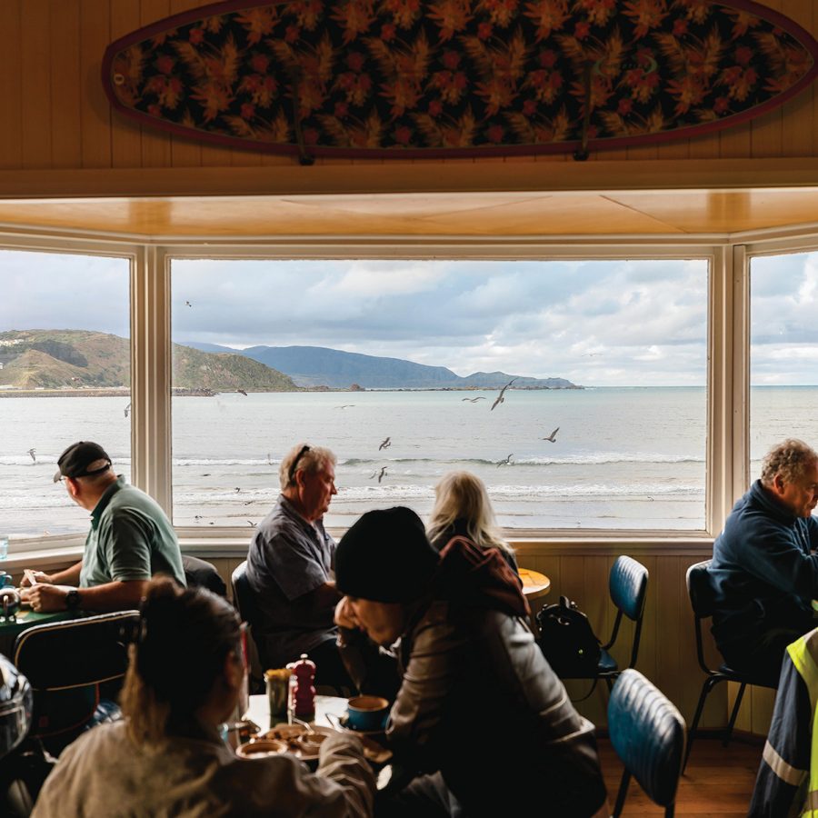 Diners sitting by the window at Maranui Cafe, with views of Lyall Bay.