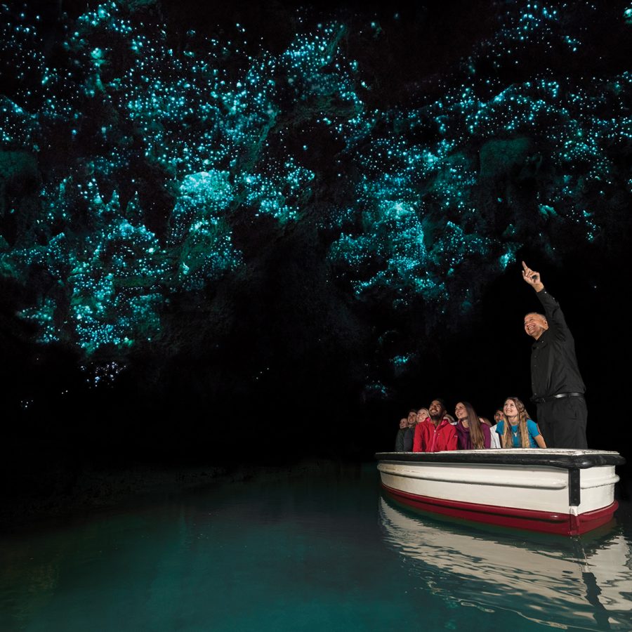 A tour guide and visitors on a boat in the Waitomo Glowworm Caves.