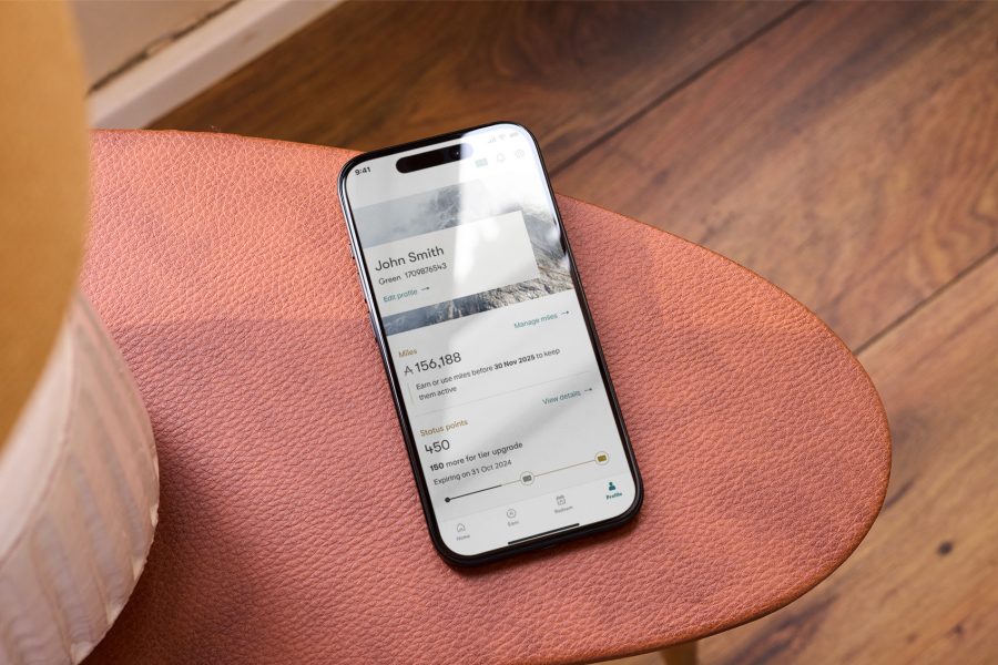 Top-down view of a smartphone on a table displaying the profile page of Asia Miles app.