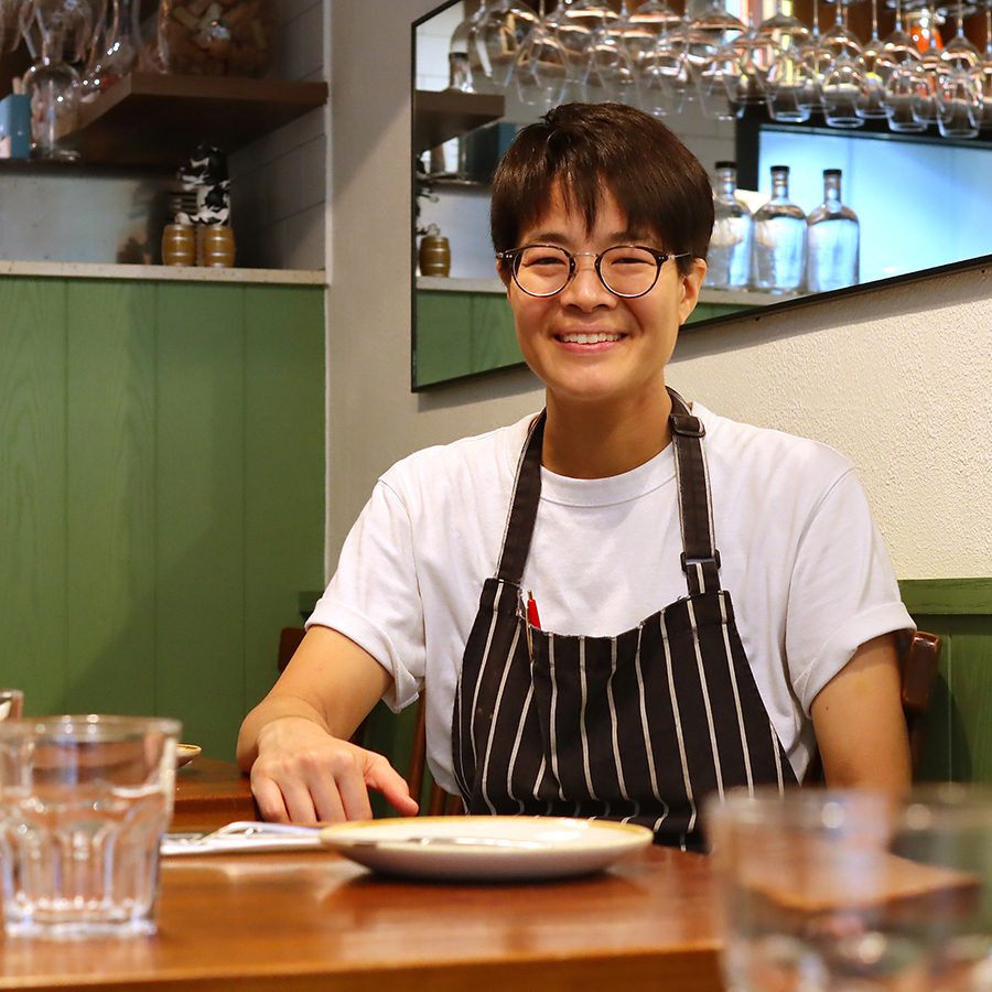 Tiff Lo, chef-owner of Jean May sits at a table in her restaurant and poses for a picture.