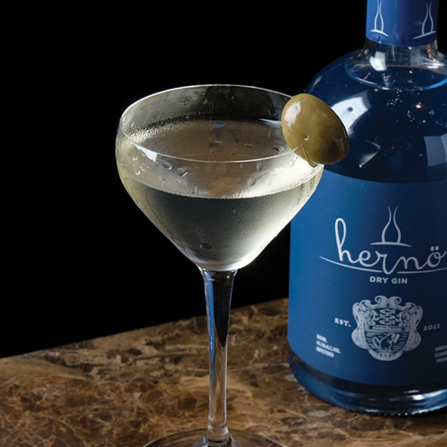 A bottle of Hernö dry gin and a glass of Hernö Dirty Martini with an olive garnish served at Embla, Hong Kong.