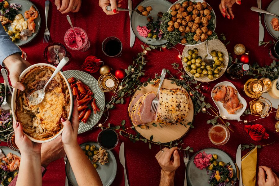 Festive dinner table spread with people passing dishes.