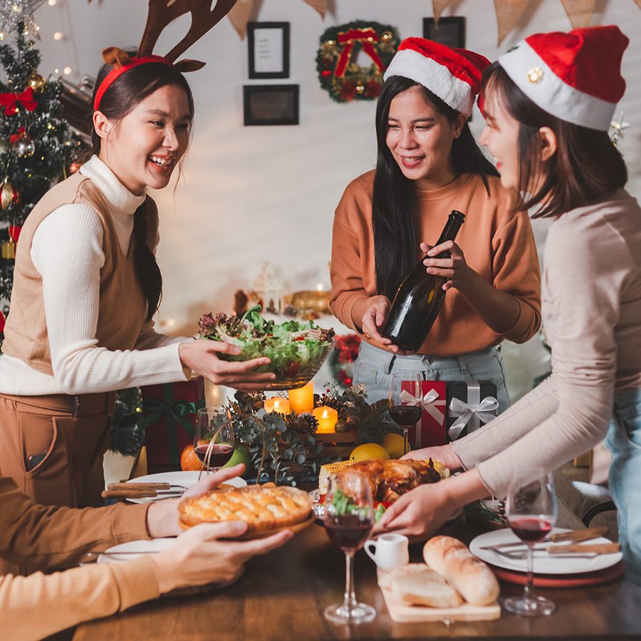 Group of people passing wine and food wearing Christmas hats and reindeer ears.