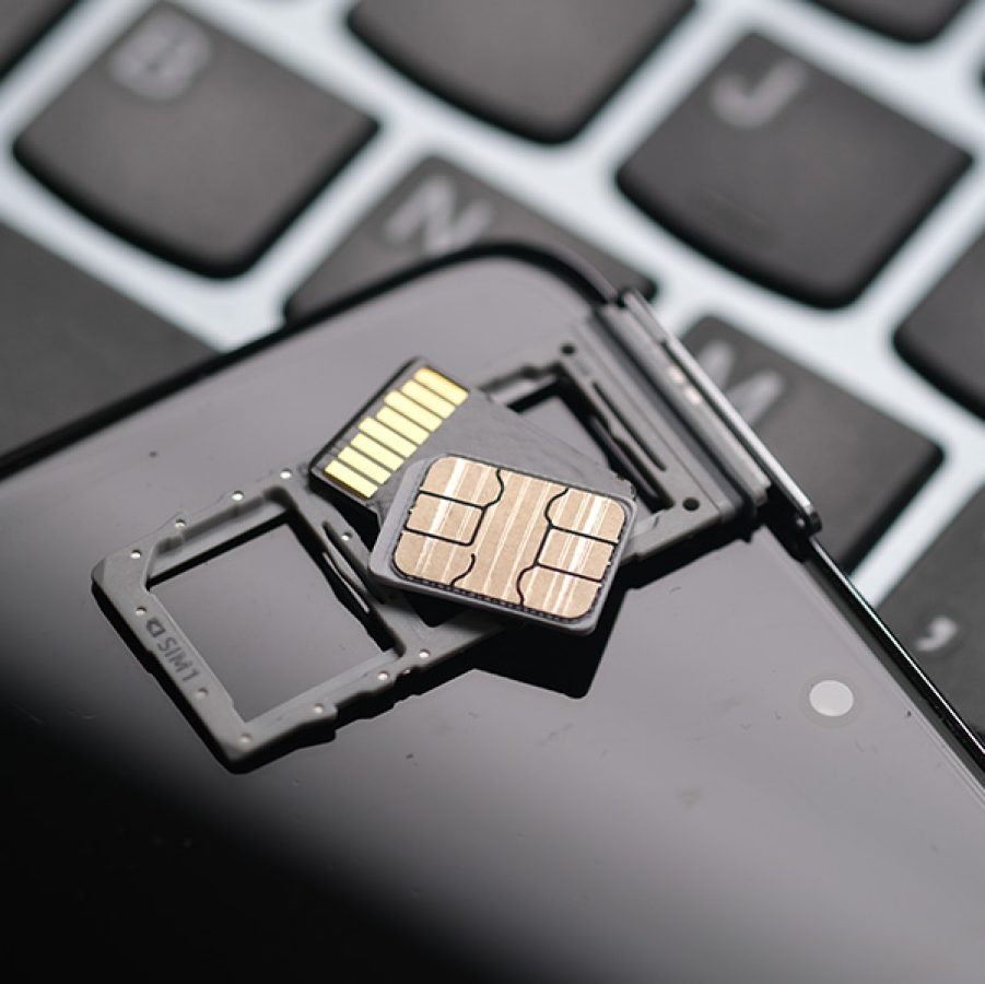 SIM cards placed atop a dual SIM card holder, on top of a mobile phone resting against a laptop keyboard.