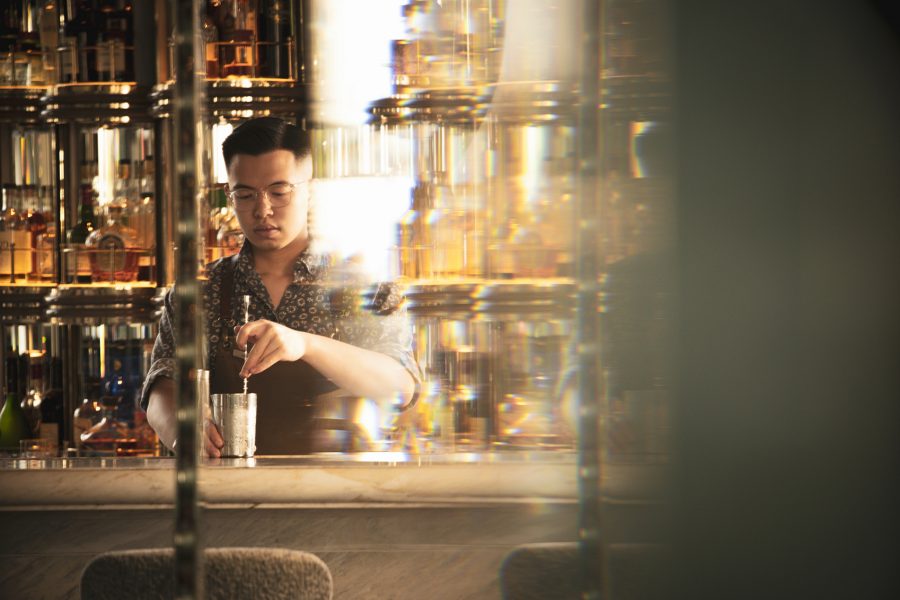 ARGO senior bartender Evan Mak behind the bar mixing a cocktail.