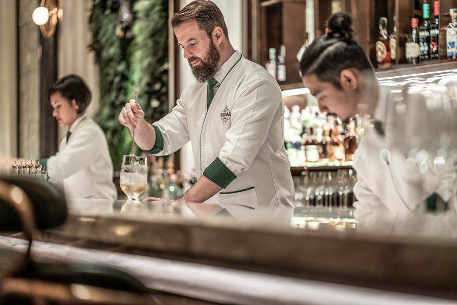 The BKK Social bar team in Bangkok behind the bar mixing cocktails.