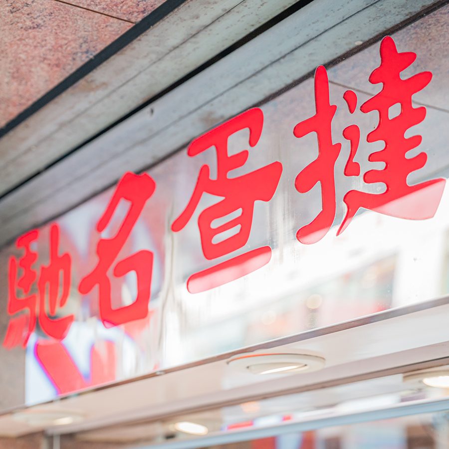 Red Chinese text on a window that advertises famous egg tarts.    A cup of coffee and a pastry on a plate  Description automatically generated   (pls pick 1-2 images)
