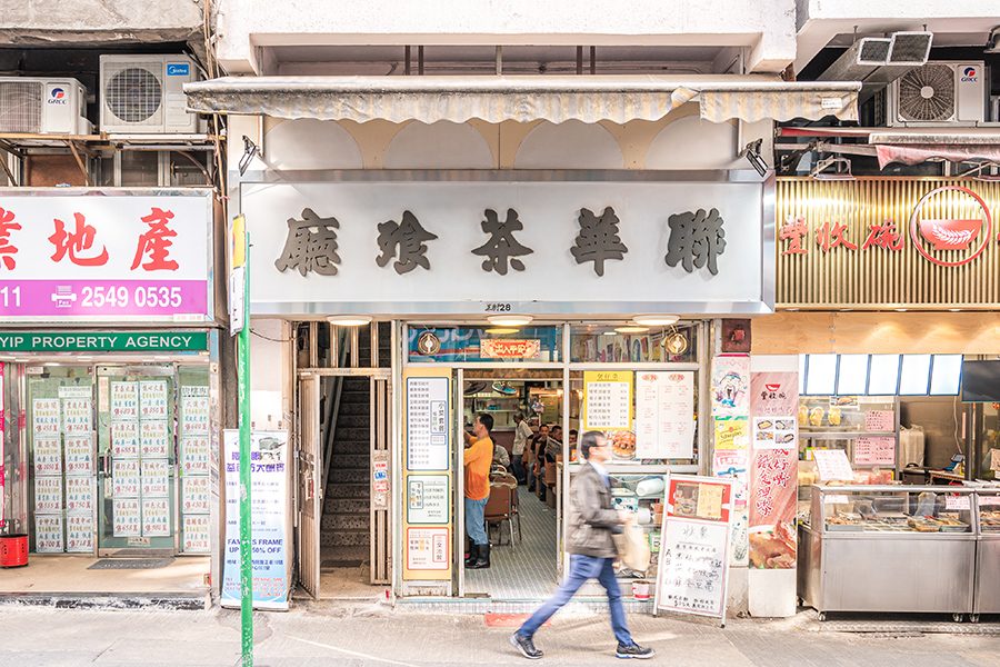 A man walking on the street in front of Luen Wah’s storefront.