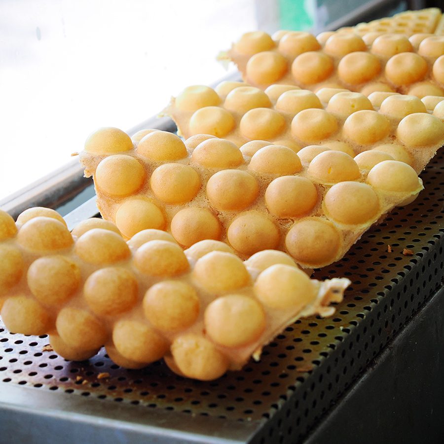 Four portions of egg waffles resting on a metal surface.