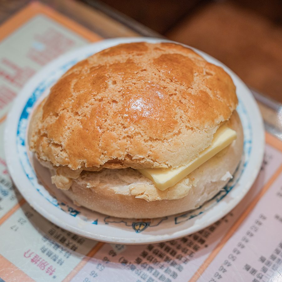 Pineapple bun with butter on a plate.