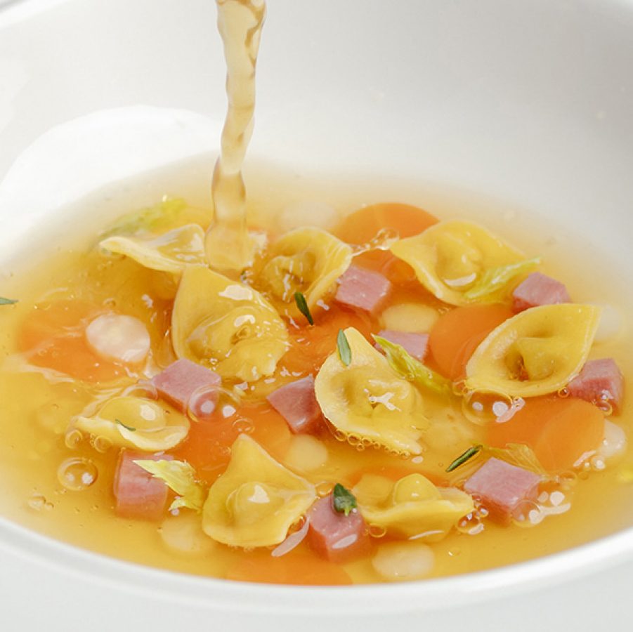 A closeup of a white plate of classic Italian homemade meat and mortadella tortellini in brodo meat broth, served at Testina in Central.